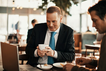 Middle aged businessman using a laptop and drinking coffee in a cafe decorated for christmas and the new year holidays