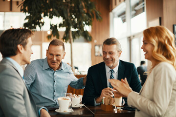 Group of middle aged business coworkers having a meeting over coffee in a cafe decorated for christmas and the new year holidays