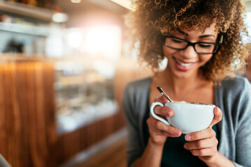 Young African American woman enjoying a cup of coffee in a cafe