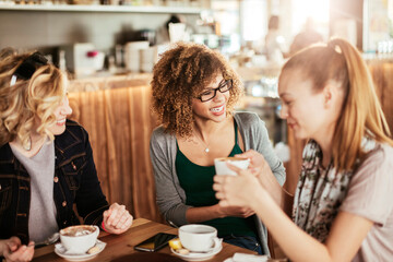 Young and diverse group of female friends enjoying coffee in a cafe