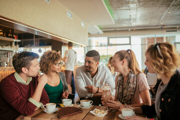 Young and diverse group of people talking while having coffee together in a cafe