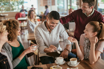 Young and diverse group of people talking while having coffee together in a cafe - Powered by Adobe