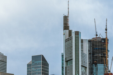 Fototapeta na wymiar hochhäuser und skyline in einer großstadt mit kränen und baumaschinen bei schönen blauen himmel