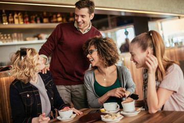 Young and diverse group of friends talking while having coffee together in a cafe