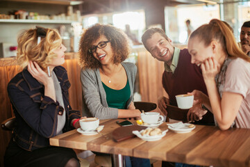 Young and diverse group of friends talking while having coffee together in a cafe