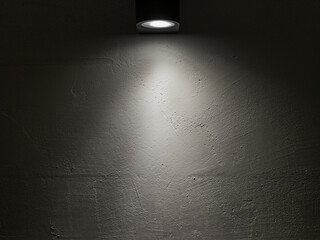 Spot light on a white wall in a dark room. - obrazy, fototapety, plakaty
