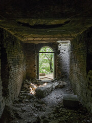 An arched exit from an old abandoned building or dungeon into the forest.