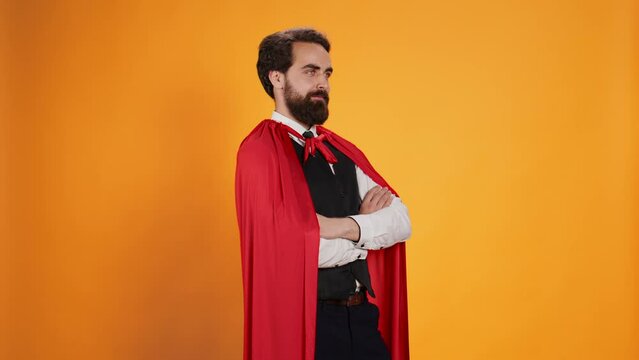 Powerful comic superhero with red cape standing against yellow background, feeling strong on camera. Dedicated valet superhuman with mantle working in restaurant dining industry.