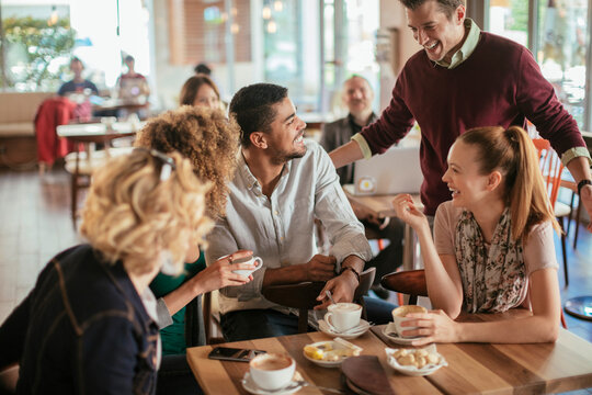 Young and diverse group of people talking while having coffee together in a cafe - Powered by Adobe
