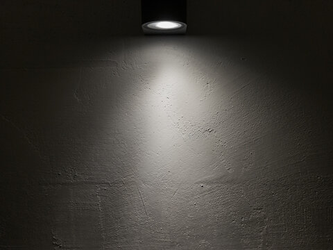 Spot light on a white wall in a dark room.