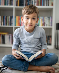 caucasian boy pupil student read book at home on the floor study learn