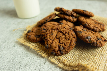 A pile of chocolate cookies with chocolate chips on top, on a textured gray table