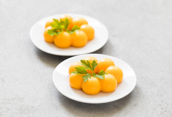 Vegan Carrot cream dessert, Panna Cotta in the shape of truffles, with parsley. On a plate. LIght grey background. Close up