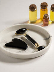 Jade face rollers and Gua sha stones for beauty facial massage therapy, Items for home treatment with skin care anti-aging tools, oils and moisturiser Cream