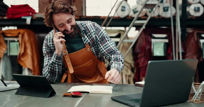 Phone call, leather workshop and craftsman take order, writing in book and listening. Smartphone, tannery factory and happy tailor talking for textile production, manufacturing and small business.