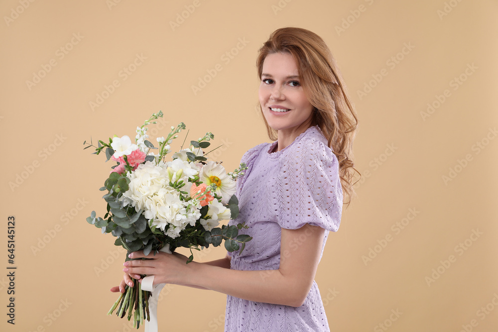 Wall mural Beautiful woman with bouquet of flowers on beige background