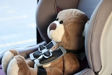 Teddy bear in child safety seat inside car