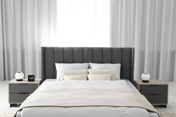 Fototapeta na wymiar Stylish bedroom in soft light colors with comfortable bed and bedside tables. Interior design