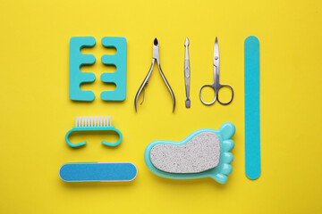 Set of pedicure tools on yellow background, flat lay