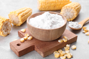 Fototapeta na wymiar Bowl with corn starch and kernels on light grey table, closeup