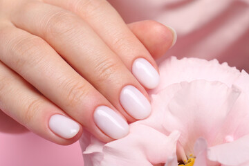 Obraz na płótnie Canvas Woman with white nail polish touching eustoma flower, closeup