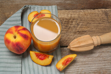 Glass of peach juice, fresh fruits and citrus reamer on wooden table, above view