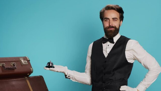 Hotel concierge presents service bell, showcasing hospitality concept and ringing for assistance. Classy bellboy or doorman helping with suitcase, luxurious formal occupation in tourism sector.
