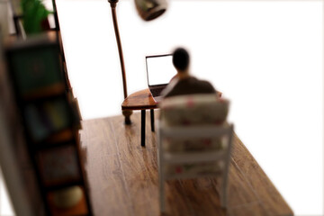 Miniature scene of a man sitting in a chair in a room looking at the blank screen of a laptop computer.