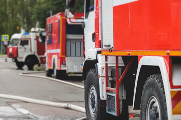 Fire fighting equipment in the city, with red fire engine truck during fire fighting operation in the city streets, vehicle and firefighters extinguish blaze, emergency and rescue service vehicle