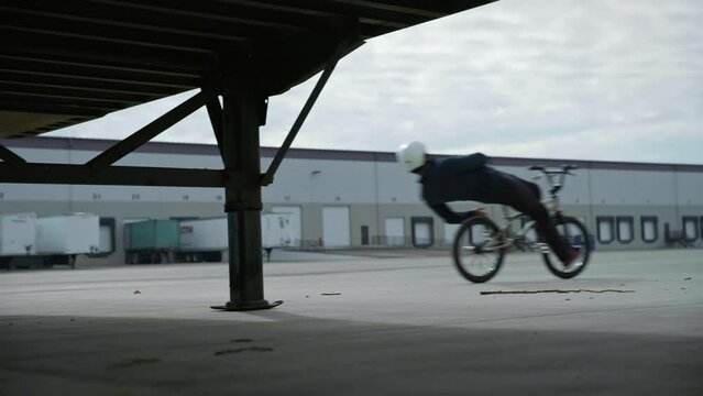 Low, Wide shot of Bike Athlete limboing under trucks