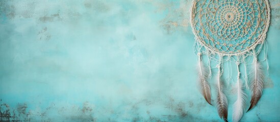 Dream catcher with lace design on textured turquoise background resembling concrete.
