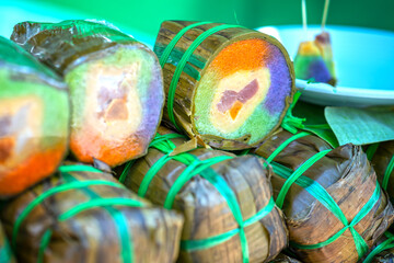 Five-colored tet cakes are sold at the market. The cake is made from colorful glutinous rice flour and meat and beans wrapped in banana leaves. Cakes are eaten during Lunar New Year in Vietnam