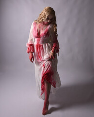  Full length portrait of  scary vampire zombie bride, wearing elegant halloween fantasy costume  dress with bloody red paint splatter. in standing walking pose. Isolated on studio background  © faestock