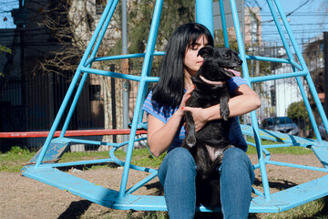 young latin woman sitting in the park with her pet