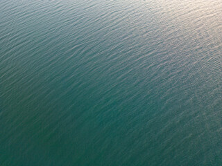 Drone shot of a calm, turquoise water surface at Praia da Ponta de Pedras, also know as beach stones tip,  between Alter do Chão and Santarém in Brasil in the setting sun; background, texture, color