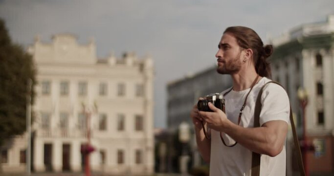 Smiling male tourist admiring sightseeing and taking photos on retro camera