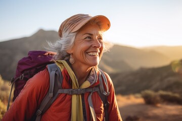 Naklejka premium Smiling portrait of a happy senior woman hiker hiking in the forest and mountains