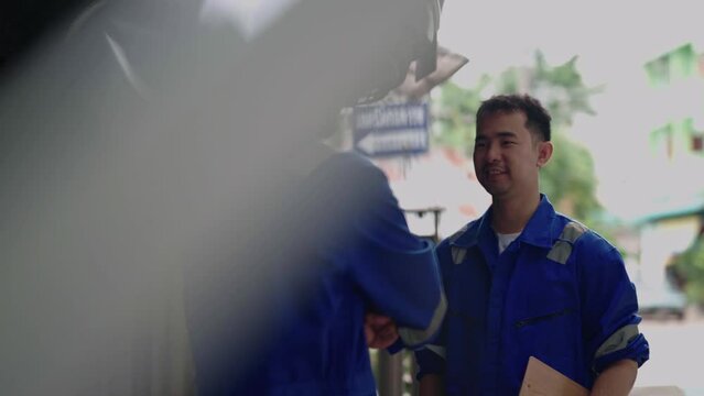 Two Asian car mechanic team technician mechanic or worker shaking hands celebrate successful together completed deal commitment at garage automotive team service center.