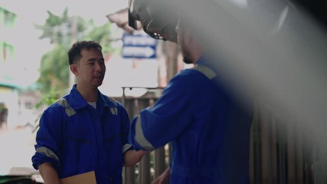 Two Asian car mechanic team technician mechanic or worker shaking hands celebrate successful together completed deal commitment at garage automotive team service center.