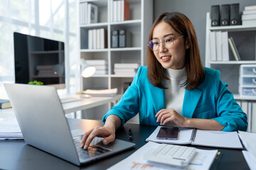 Asian business woman working using laptop computer, marketing report with calculator document on...