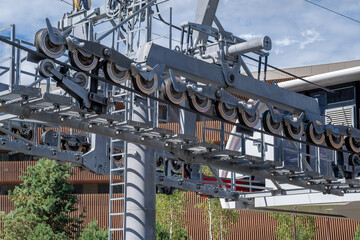 Fototapeta premium Ropeway mechanism and cable support pylon. Close-up of a cable car cabin against the sky. Cable car trip to viewpoints in the mountains. During the trip by cable car Tourists enjoy beautiful views 