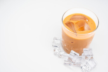 Glass of thai iced tea with ice cube on white background.