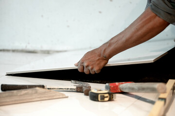 Laying ceramic tiles, close up hands of the worker are laying the ceramic tile on the floor