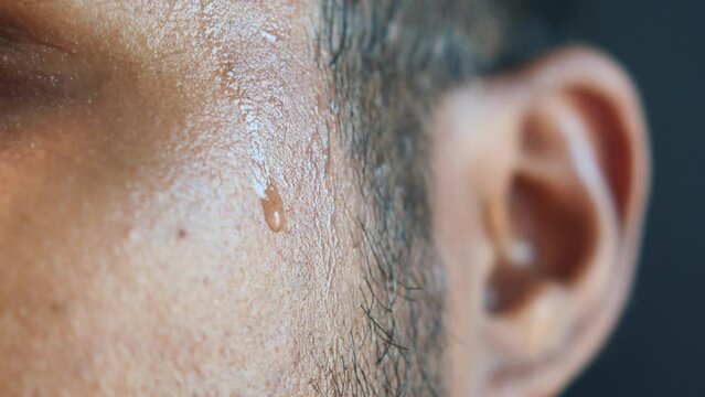 closeup of sweat on forehead against dark background ,