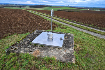 Verzinkte quadratische Schachtabdeckung mit Dunsthut mit Betonrahmen auf einem Feld	
