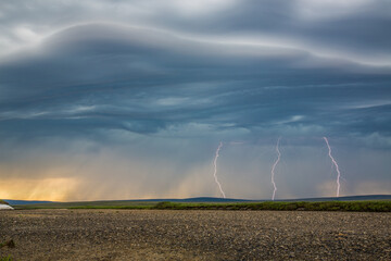 Lightning bolts descend from dark clouds over the tundra of Alaska's northwest arctic and the...