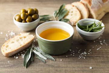Olive oil, olives and slices of bread on wooden background