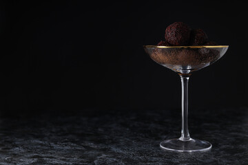 Brigadeiro in cocktail glass on dark background, space for text
