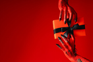 Spooky, red monster hands hold a gift