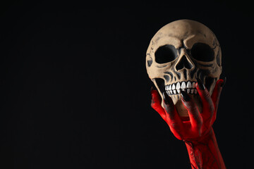 Creepy, red hands of the monster hold the skull